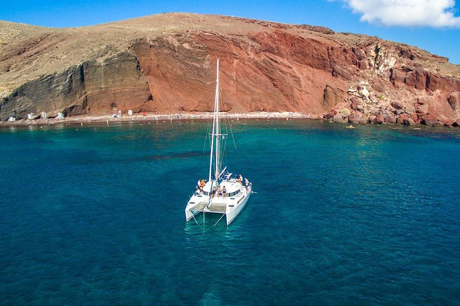 Santorini Half Day Catamaran Private Cruise incl. Meal, Drinks & Free Transport - Red Beach and Akrotiri energy: the volcanic color show up close